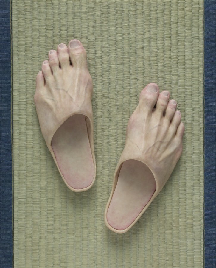 畳の上のリアルな足の形をしたスリッパ